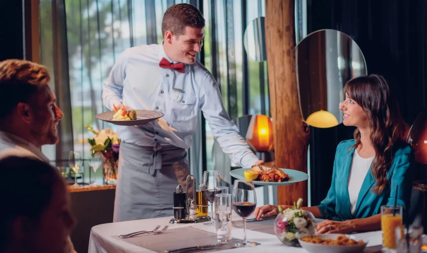 A waiter serving food to his guests