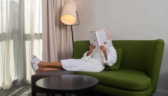 a woman relaxing while reading a newspaper in the premier room of the CUE hotel in Montenegro